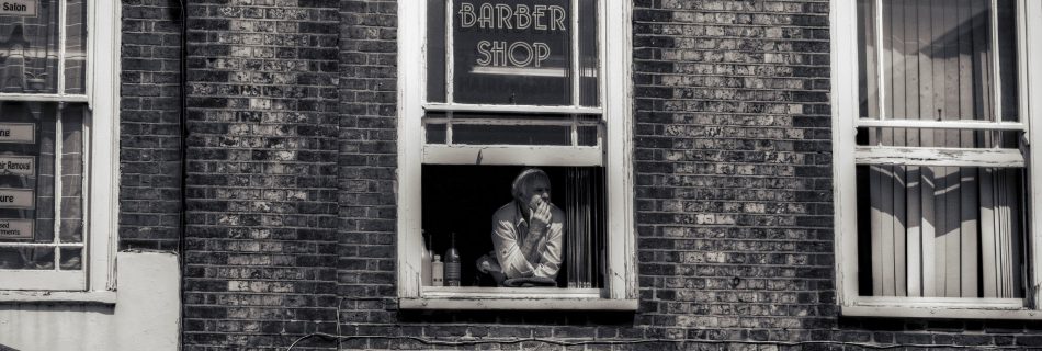 Man peering out of a Barber Shop window